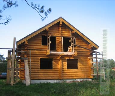 Строительство деревянного рубленого дома на стадии укладки крыши черепицей